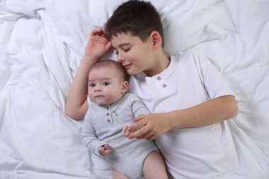 Yatakta sevimli küçük kardeşler, üst manzara.