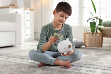 Çocuk evdeki domuz kumbarasına cep harçlığı koyuyor.