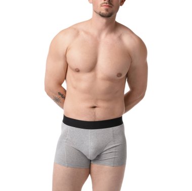 Beyaz arka planda açık gri iç çamaşırlı genç adam, yakın plan.