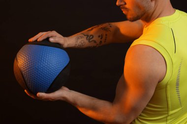 Siyah arka planda tıp topu olan adam, yakın plan.