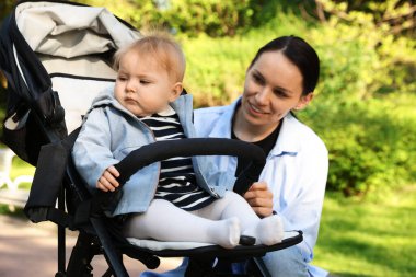 Parkta bebek arabasında sevimli bebeğiyle annesi