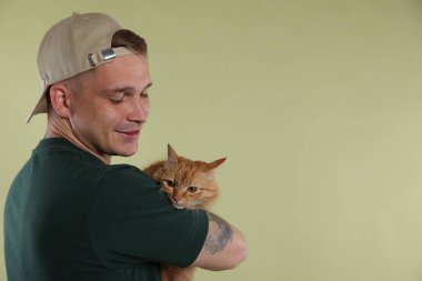 Açık yeşil arka planda sevimli kızıl kedili adam, metin için boşluk