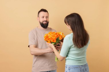 Adam bej arka planda sevgili karısına güzel laleler sunuyor.