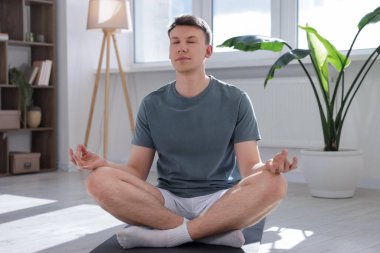 Genç adam evde yoga yapıyor.