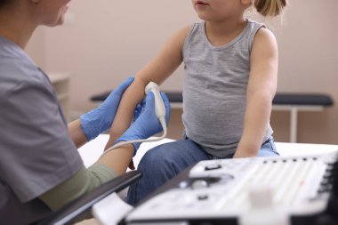 Sonograf, klinikte küçük bir kızın kolunun ultrason muayenesi yapıyor.