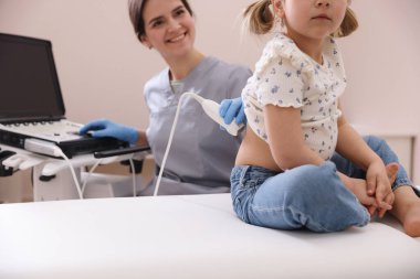 Küçük kızın böbrek ultrasonu muayenesini klinikte yapan sonograf.