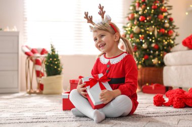 Evde hediye kutularıyla Noel kostümü giymiş küçük kız.