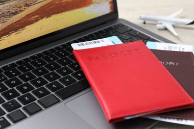 Pasaportlar, uçuş biletleri, uçak modeli ve dizüstü bilgisayar masada, yakın plan.