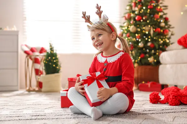 Evde hediye kutularıyla Noel kostümü giymiş küçük kız.