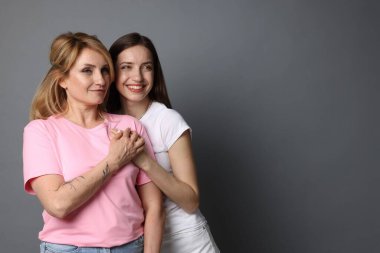 Anne ve kızı gri arka planda sarılıyorlar. Metin için boşluk