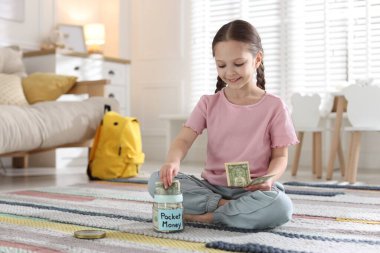 Kız evde cep harçlığını kavanoza koyuyor. Metin için boşluk