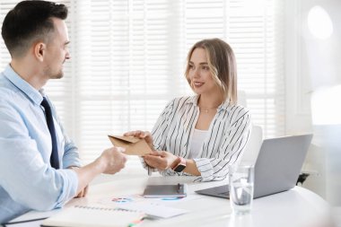 Para bonusu. Patron ofisteki çalışana zarf veriyor.