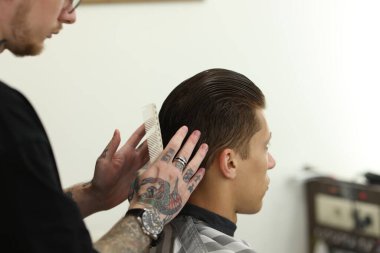 Berber dükkanında müşteriyle çalışan profesyonel berber, yakın plan.