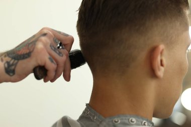 Berber dükkanında müşteriyle çalışan profesyonel berber, yakın plan.