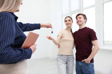 Tabletli emlakçı evde yeni sahibine ev anahtarını veriyor.