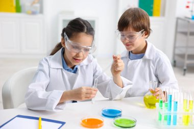 Çocuklar içeride masada kimyasal deneyler yapıyorlar.