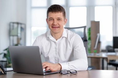 Ofiste masada dizüstü bilgisayarda çalışan adam