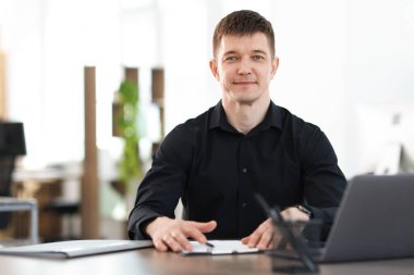 Ofiste masa başında çalışan yakışıklı adam.