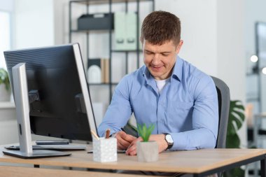 Ofiste masa başında çalışan yakışıklı adam.