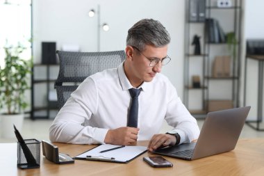 Ofiste masada dizüstü bilgisayar üzerinde çalışan işadamı