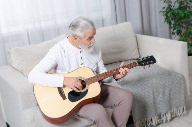 Rahatlatıcı hobi. Son sınıf öğrencisi evdeki kanepede gitar çalıyor.