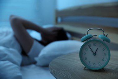 Evde yatakta uykusuzluk çeken sinirli genç kadın, alarma odaklan.