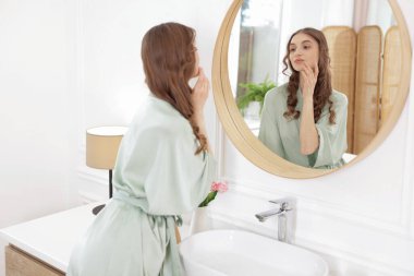 Güzel bir kadın aynada kendine bakıyor.