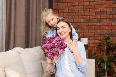 Anne ve kızı evde bir buket leylak çiçekleriyle