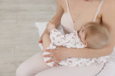 Anne, küçük bebeğini evde emziriyor, yakın plan. Metin için boşluk