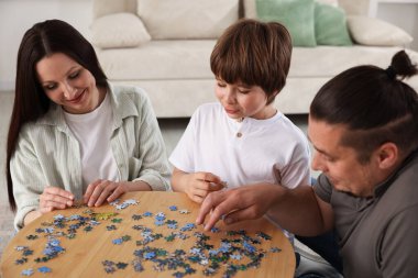 Aileler ve oğulları kapalı bir masada bulmaca çözüyorlar.