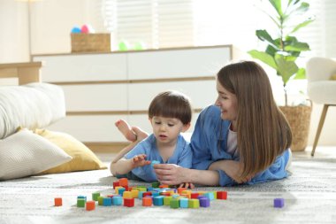 Anne ve oğlu evde renkli küplerle oynuyorlar. Metin için boşluk