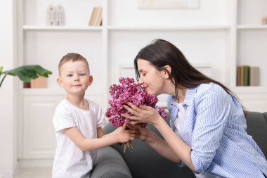 Anne ve oğlu evde bir buket leylak çiçekleriyle