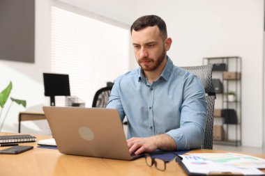 Ofiste masada dizüstü bilgisayarda çalışan adam