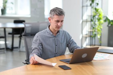 Ofisteki masada belgelerle çalışan bir işadamı.