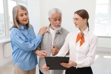 Gülümseyen bir emlakçı pano ile evde çiftlerle çalışıyor.