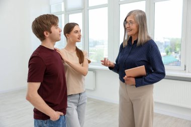 Tabletle gülümseyen emlakçı evde çiftlerle çalışıyor.