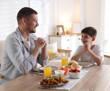 Baba ve oğul akşam yemeğinden önce evde dua ediyorlar.