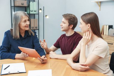 Tabletli emlakçı ofiste bir çiftle çalışıyor.