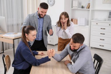 İş adamları, ofisteki tahta masada bilek güreşi yapıyorlar.