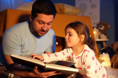 Babası evde kızına masal okuyor.