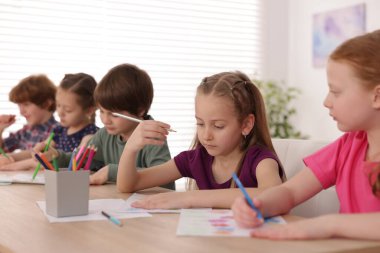 Çocuklar kapalı mekanlarda resim yapıyor, seçici bir odak noktası var. Çizim yapmayı öğrenmek