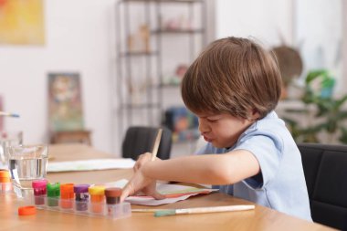 Masada resim yapan sevimli bir çocuk, mesaj için yer var. Çizim yapmayı öğrenmek