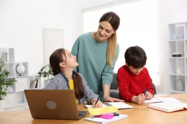 Anne, çocuklarına ev ödevlerinde yardım ediyor.