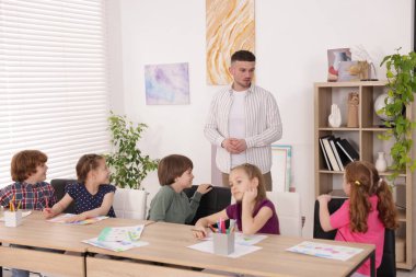 Çocuklara resim dersinde resim yapmayı öğreten bir adam.