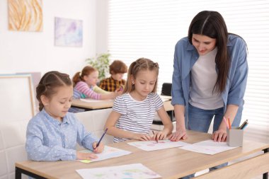 Çocuklara resim yapmayı öğreten kadın kapalı alanda resim dersi veriyor, seçici bir odak.