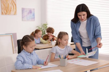Çocuklara resim yapmayı öğreten kadın kapalı alanda resim dersi veriyor, seçici bir odak.