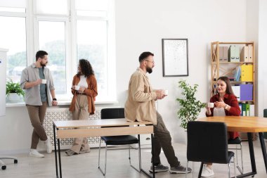 Ofiste kahve molası sırasında iş arkadaşları sohbet ediyor.