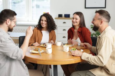 İş arkadaşları öğle arasında ofiste sohbet ediyorlar.