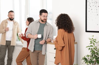 Ofiste kahve molası sırasında iş arkadaşları sohbet ediyor.