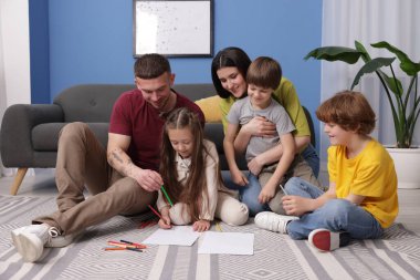 Ebeveynler çocuklarına evde yerde çizim yapmayı öğretiyor.